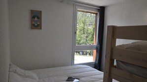 Ein Zimmer mit einem Bett, einem Fenster und einem Bild an der Wand.