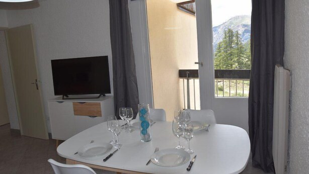 Ein Essbereich mit einem Tisch für vier Personen, einem Flachbildfernseher und Bergblick durch große Fenster.