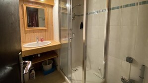 Ein Badezimmer mit einem Holzwaschtisch, einer Duschkabine aus Glas und einer gefliesten Wand.
