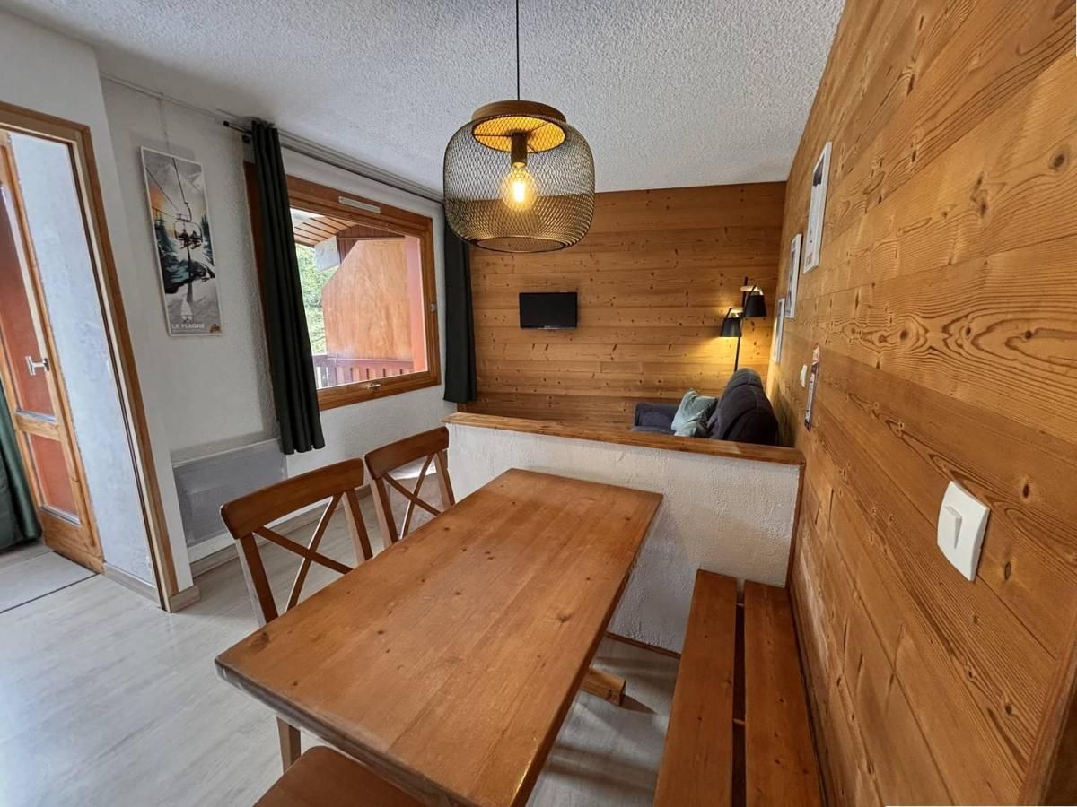 A wooden interior with a dining table, chairs, a hanging light fixture, and a bench.