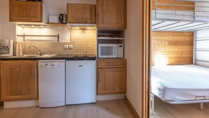 A compact kitchen with wooden cabinets, a dishwasher, a microwave, and a sink.