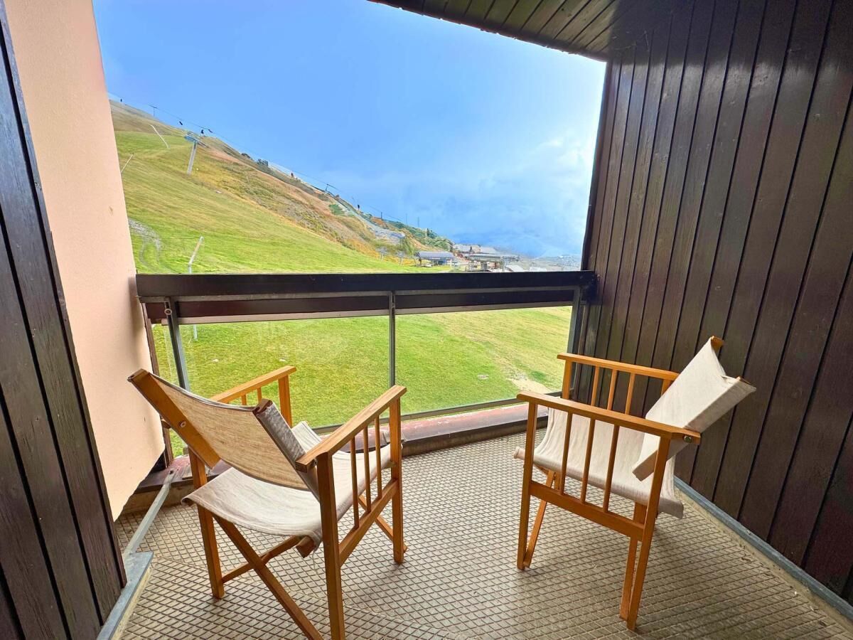 Een balkon met twee houten stoelen en uitzicht op een groen landschap.