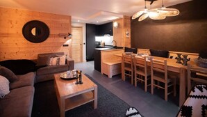 Un salon chaleureux avec un canapé, une table basse et un coin repas comprenant des chaises et une table en bois.