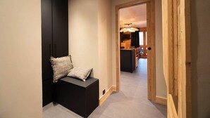 Un couloir menant à un espace cuisine équipé d’un banc et de coussins.