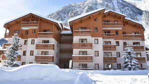 Un hotel de varios pisos con balcones de madera y una montaña nevada al fondo.