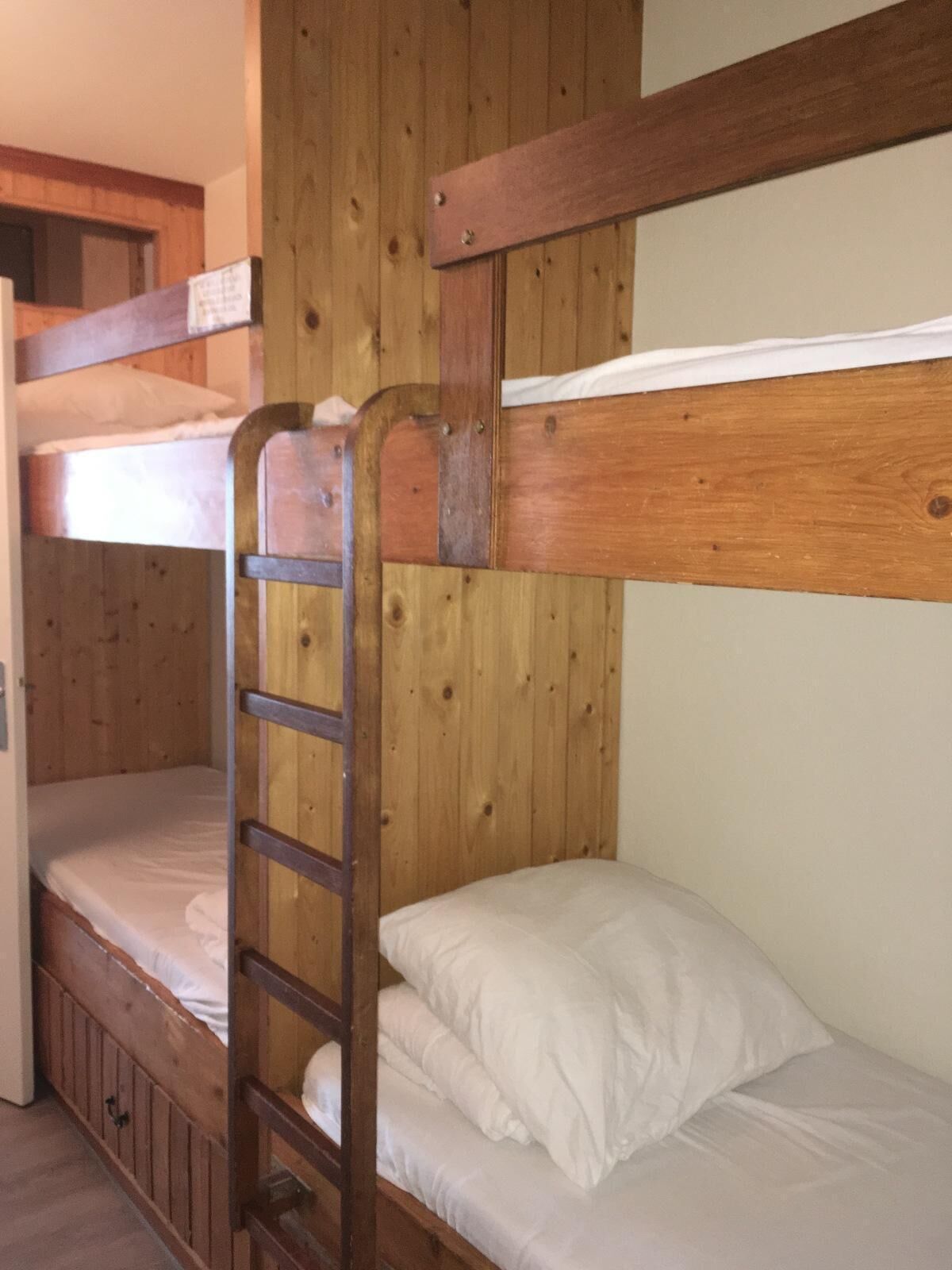Een slaapkamer met stapelbedden, houten wanden en een trap.