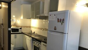 A compact kitchen with white cabinets, a built-in oven, a microwave, and a refrigerator. - 100m from resort center, 1st floor, view mountain, balcony, tv, 27m², Gourette (Eaux-Bonnes)