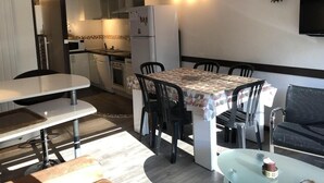 A compact kitchen with a dining area, a refrigerator, and a television mounted on the wall. - 100m from resort center, 1st floor, view mountain, balcony, tv, 27m², Gourette (Eaux-Bonnes)