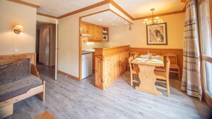 Ein gemütliches Wohnzimmer mit einer Couch, einem Esstisch mit Stühlen und einer Küchenzeile mit Holzschränken und einer Mikrowelle.