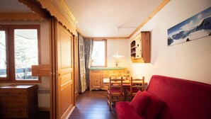 Una habitación acogedora con un sofá rojo, armarios de madera, una mesa de comedor y vistas al exterior.