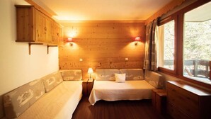 Acogedora habitación de cabaña con dos camas, paredes de madera y una ventana con cortinas.