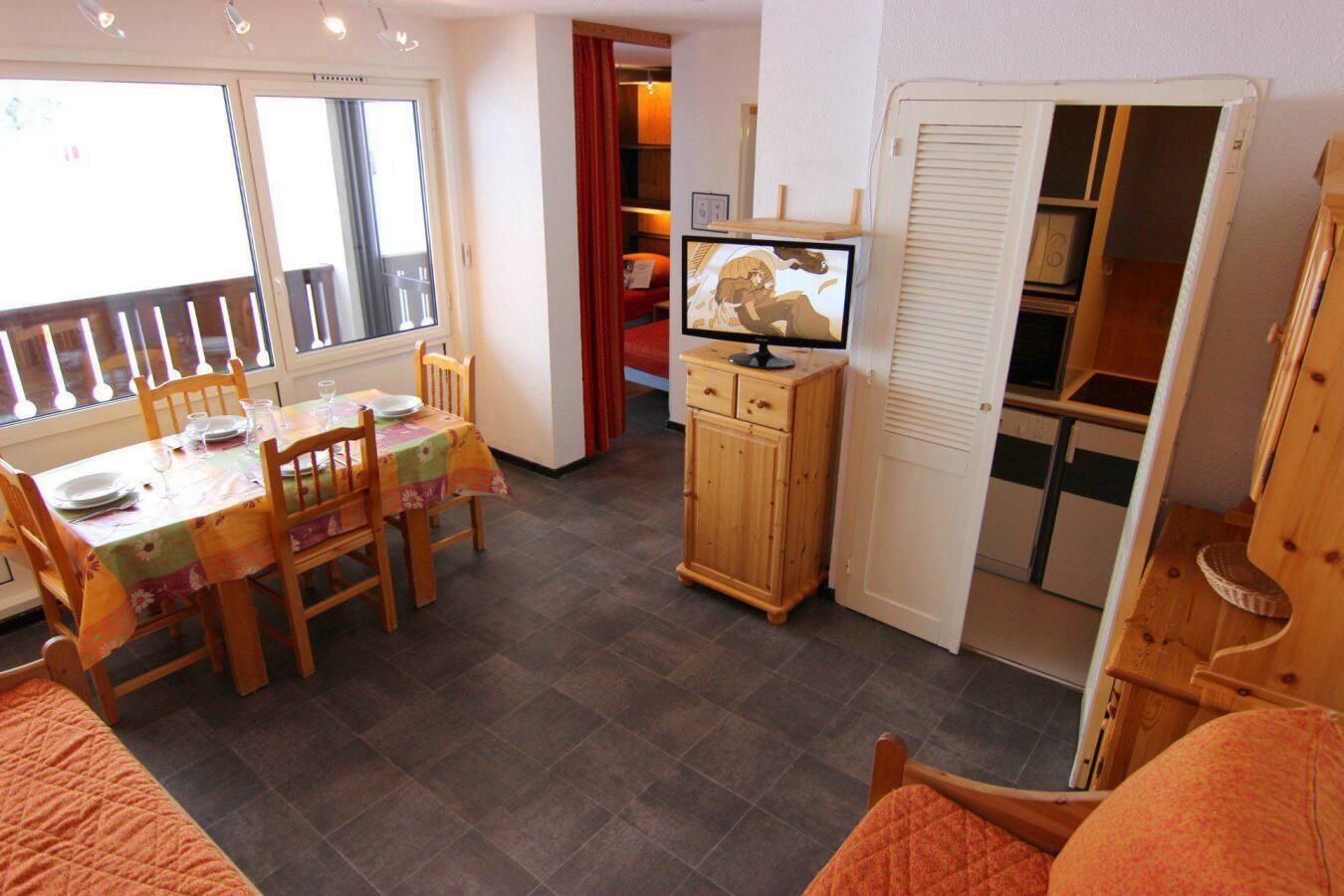 A dining area with a table set for four, a television on a cabinet, and a sliding door closet.