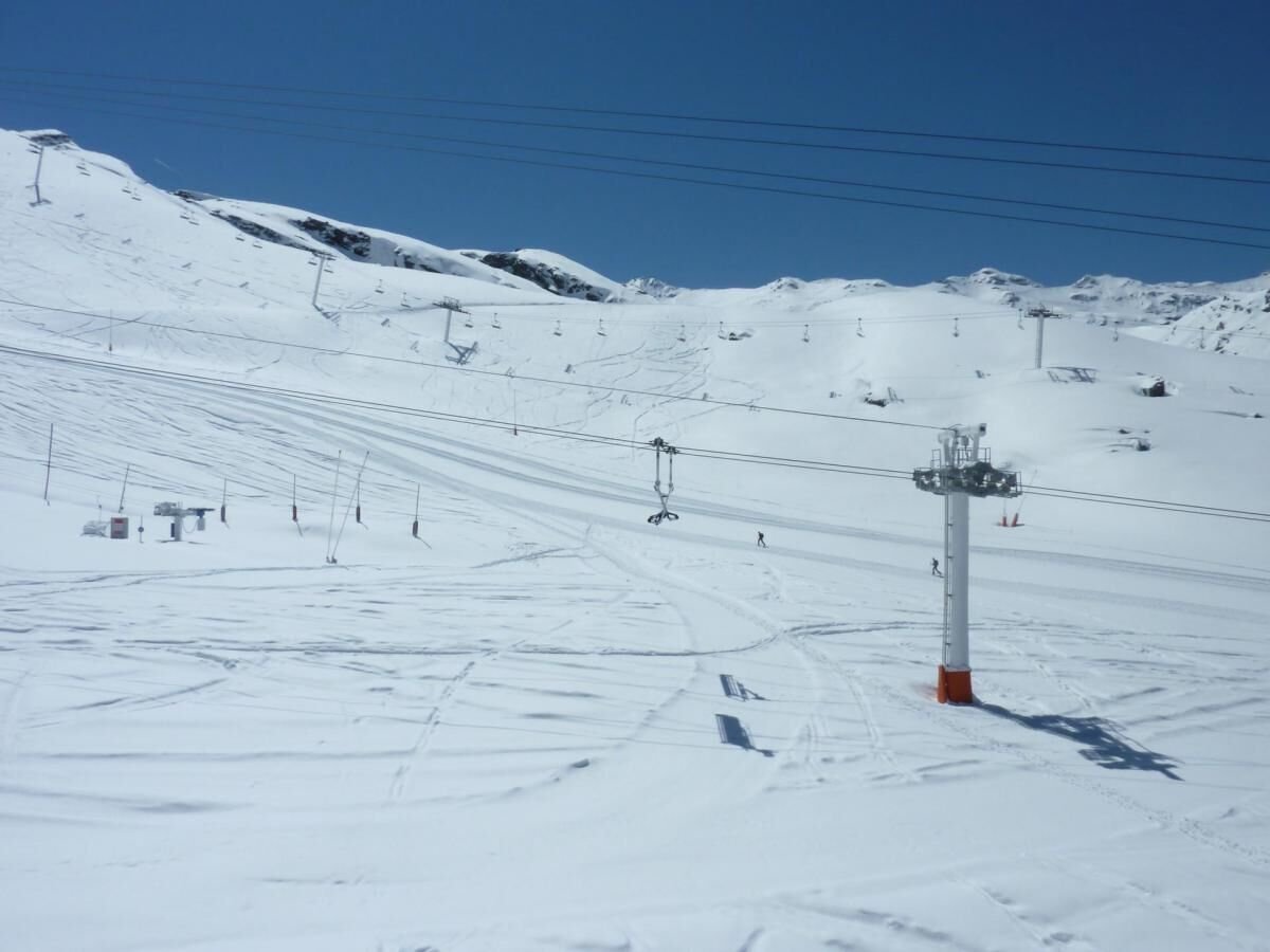 Une piste de ski enneigée, avec des remontées mécaniques et des pistes balisées.