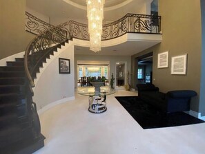 Stunning grand staircase and elegant chandelier set the tone for a luxurious atmosphere.