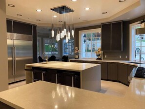 Enjoy cooking in this well-lit kitchen with a central island, bar stools, and a stainless steel refrigerator.