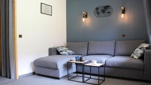 Ein modernes Wohnzimmer mit grauem Sofa, einem kleinen Beistelltisch und dekorativen Wandleuchten.