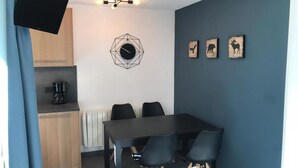 Ein kleines Zimmer mit dunkelblauer Wand, einer runden Uhr und drei gerahmten Tierbildern.