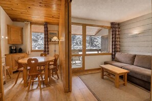 A cozy room with a wooden dining table and chairs, a sofa, and a bench.