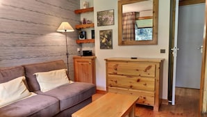 Ein gemütliches Wohnzimmer mit einem braunen Ledersofa, einem Holztisch und einer Kommode mit Schubladen.