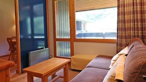 Ein Zimmer mit einem Holztisch, einer Couch und einem Fenster mit Jalousien.