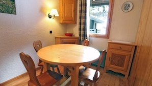 Ein Holzespeisesaal mit sechs Stühlen, einer Wandlampe, einem Fenster mit Vorhängen und einem kleinen Schrank mit einer Dekorplatte.
