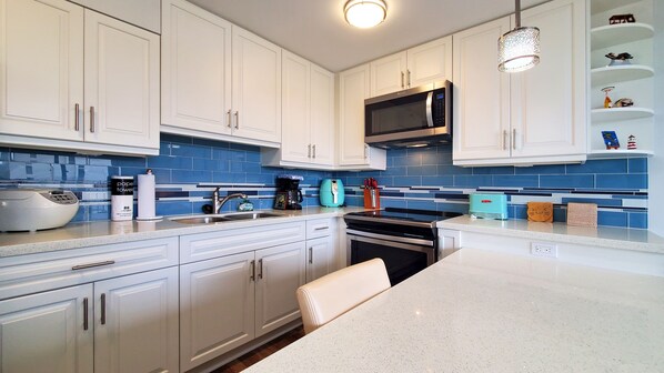 Una cocina moderna con armarios blancos, un microondas de acero inoxidable y un salpicadero de azulejos azules.