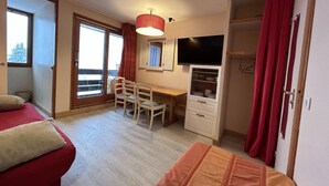 A bedroom with two beds, a desk, a chair, a TV, and a wardrobe. - 75m from shops, 2nd floor, view valley, balcony, ski locker, 27m², Méribel-Mottaret (Méribel - Les Allues)