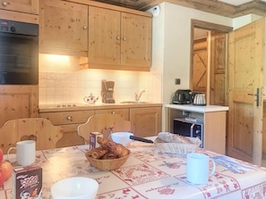 A cozy kitchen with wooden cabinets, a coffee maker, and a table set with bread and a mug. - 200m from shops, Ground floor, terrace, tv, ski locker, 35m², Saint Martin de Belleville (Saint-Martin-de-Belleville)