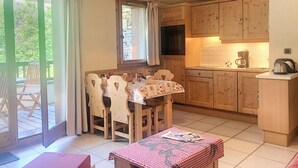 Uma cozinha acolhedora com armários de madeira, uma mesa de jantar com cadeiras e uma mesa pequena com toalha xadrez.