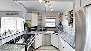 Una cocina moderna con armarios blancos, un refrigerador de acero inoxidable, un lavavajillas y una encimera de granito.