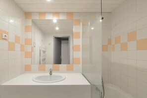 Ein Badezimmer mit einem weißen Waschbecken, einem Spiegel und orangefarbenen Fliesen.