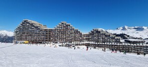 Um hotel grande, com vários andares e um design arquitetônico singular, localizado em uma área montanhosa coberta de neve.