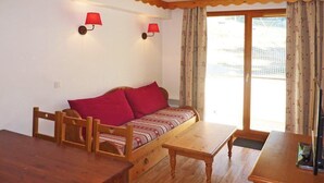 A cozy room with a wooden sofa, a dining table, and two wall-mounted lamps.