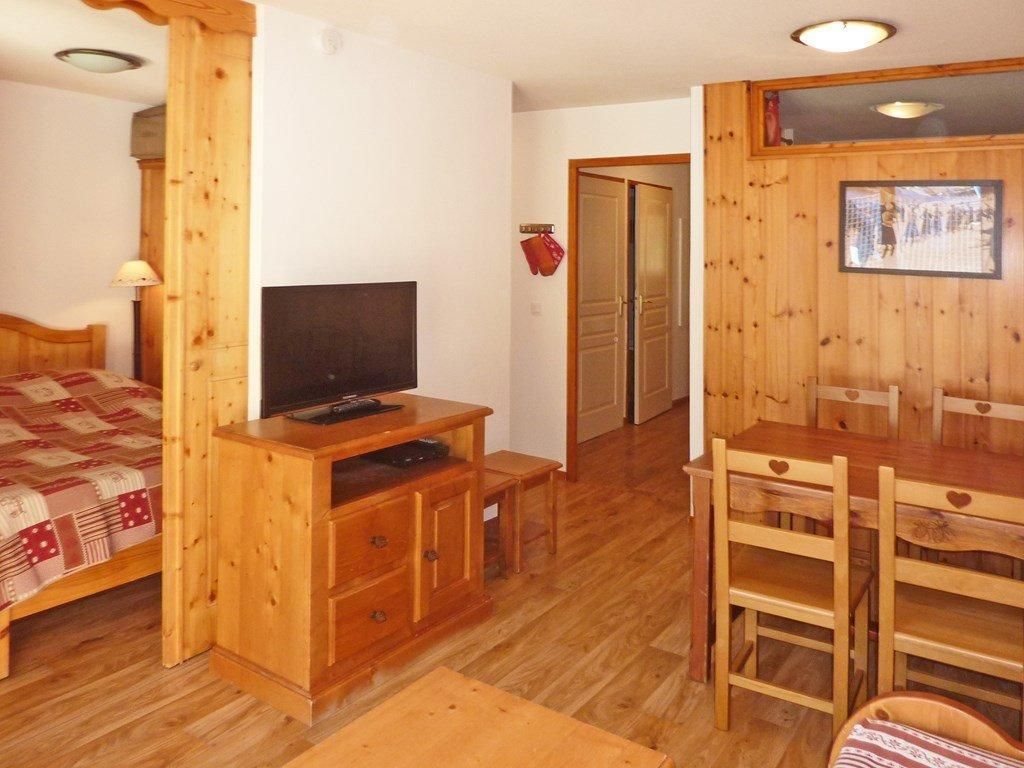 Ett rum med en säng, trämöbler, en tv och en matplats.