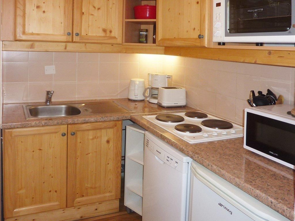 Una cocina con armarios de madera, lavavajillas, microondas y estufa.