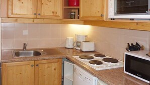 A kitchen with wooden cabinets, a stainless steel sink, a built-in dishwasher, a microwave, and a stove.