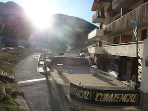 A commercial building with a balcony, a paved area with benches, and a mountain in the background.