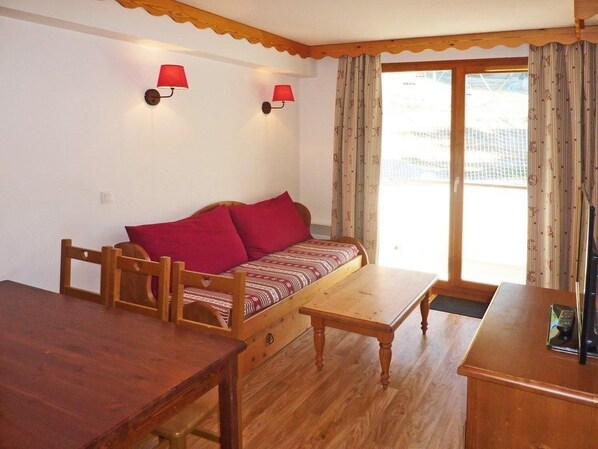 A cozy room with a wooden sofa, a wooden table, and two wall-mounted lamps.