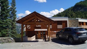 A wooden lodge with a covered entrance, a stone wall, and a car parked in front. - Ground floor, terrace, tv, 40m², Pra Loup (Pra Loup)