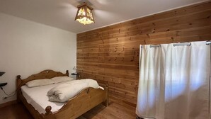 A bedroom with a wooden bed, a nightstand, a wall-mounted lamp, and a curtain. - Ground floor, terrace, tv, 40m², Pra Loup (Pra Loup)