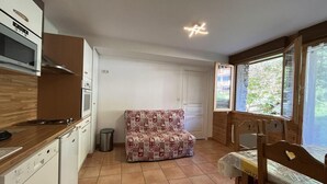 A compact kitchen with white cabinets, a wooden countertop, a built-in oven, and a dining area with a table and chairs. - Ground floor, terrace, tv, 40m², Pra Loup (Pra Loup)