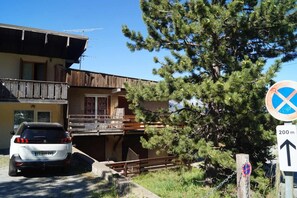A building with a balcony, a parked car, and a sign indicating a 200m distance. - 200m from ski slopes, balcony, tv, 38m², Pra Loup (Pra Loup)