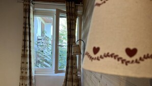 A room with a window, curtains, a radiator, and a wooden wall.
