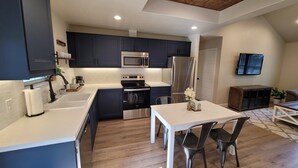 A modern kitchen with dark cabinets, stainless steel appliances, and a white countertop.