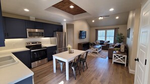 A modern kitchen with dark cabinets, stainless steel appliances, and a white dining area.