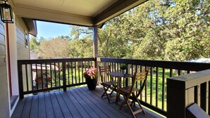 A wooden deck with a railing, a table, and two chairs.