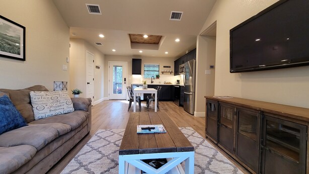 A modern kitchen with a dining area, a flat-screen TV, and a cozy living space with a sofa and coffee table.