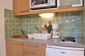 Compact kitchenette with microwave, coffee maker, and refrigerator.