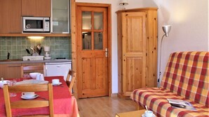 A compact kitchen with a microwave, a dining table with chairs, and a wooden cabinet. - 50m from ski slopes, 5th floor, balcony, tv, ski locker, 23m², Risoul (Risoul)
