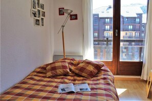 Relax in this inviting bedroom with a large bed, book and floor lamp, and framed pictures on the walls.